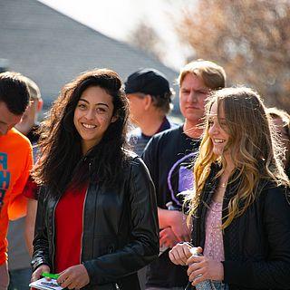 A group of students gather in a group outside. A female student smiles toward the camera.